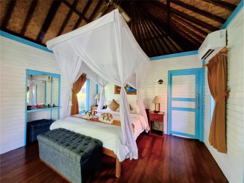 ein Schlafzimmer mit einem Himmelbett in der Unterkunft The Akah Cottage in Nusa Lembongan