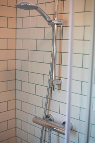 a shower head in a bathroom with white tiles at Dimora Campo delle Mura - Charming House in Acquaviva Picena