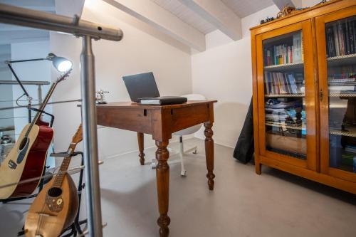 a room with a desk with a laptop and a guitar at Dimora Campo delle Mura - Charming House in Acquaviva Picena