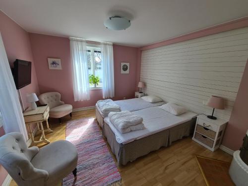 a bedroom with two beds and two chairs and a television at Slussen Rum Söderköping in Söderköping
