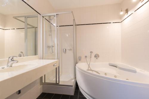 ein weißes Bad mit einer Badewanne und einer Dusche in der Unterkunft Amrâth Hotel Alkmaar in Alkmaar