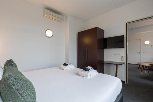 a bedroom with a large white bed and a kitchen at Amrâth Hotel Alkmaar in Alkmaar