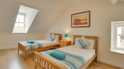 2 camas en una habitación con 2 ventanas en Carreg Lwyd Farmhouse, en Port Eynon