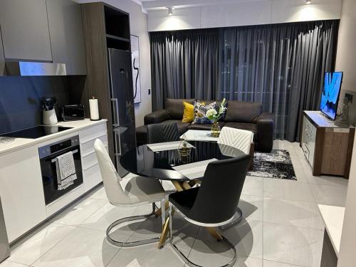 a kitchen and living room with a table and chairs at Triology Menlyn Maine Residences in Pretoria