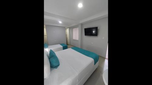 a bedroom with two beds and a tv on the wall at Bm-7 room near the sea with air conditioning and WIFI in Cartagena de Indias