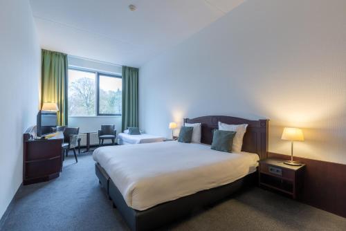 a hotel room with a large bed and a desk at Amrâth Hotel Alkmaar in Alkmaar