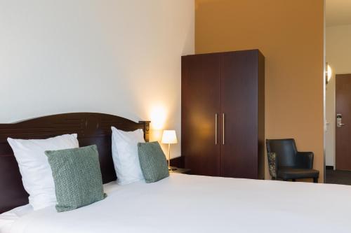 a hotel room with a large bed and a chair at Amrâth Hotel Alkmaar in Alkmaar