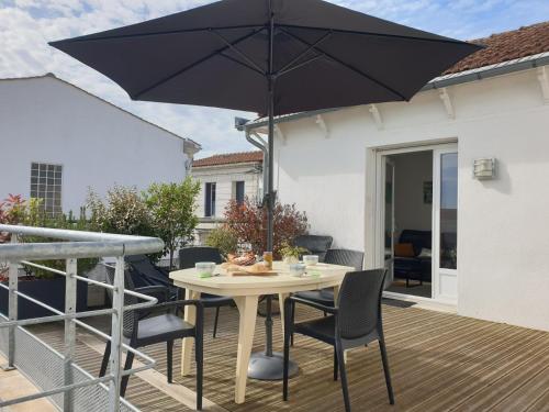 een tafel met stoelen en een parasol op een terras bij La Belle Cordière in Saint-Trojan-les-Bains