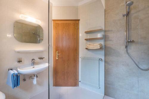 ein Bad mit einem Waschbecken und einer Dusche mit einem Spiegel in der Unterkunft Taufner Apartement C 103 in Partschins