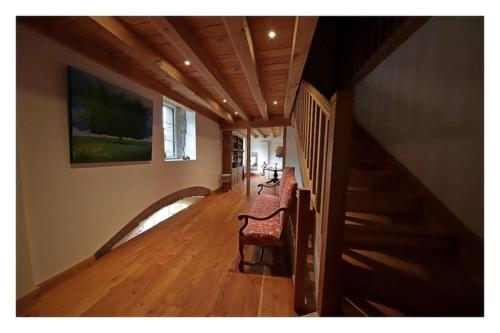 a hallway of a house with a staircase and a chair at LES CHAMBRES DE LIANE in Cerdon