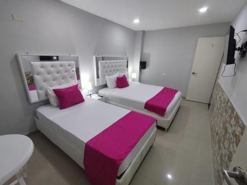 two beds in a hotel room with pink and white sheets at Bm-1 room near the sea with air conditioning and WIFI in Cartagena de Indias