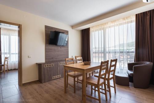 a dining room with a table and chairs and a television at Balchik Sea View Apartments in Princess Residence in Balchik