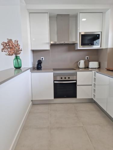 a white kitchen with white cabinets and appliances at Maktub @ Oásis Mar in Portimão