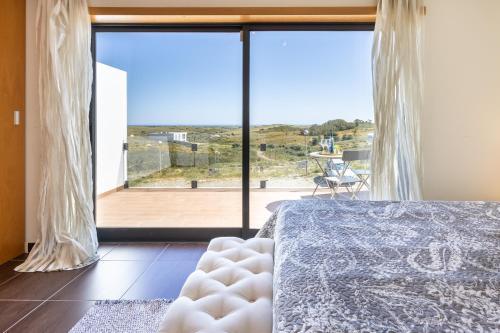a bedroom with a bed and a large window at Margarida Sun House Ocean View in Raposeira