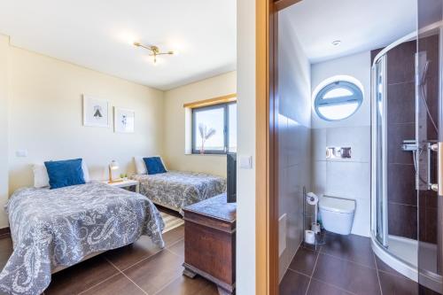 a bedroom with two beds and a shower at Margarida Sun House Ocean View in Raposeira