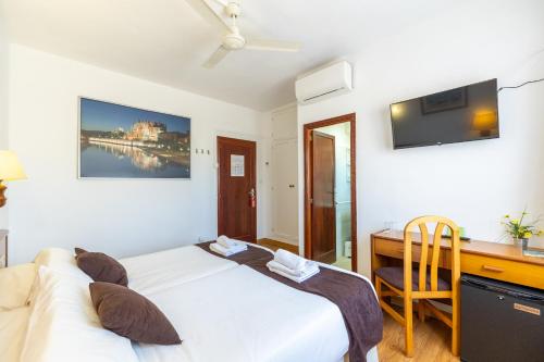 a bedroom with a bed and a desk and a computer at Hostal Doris in Colònia de Sant Jordi