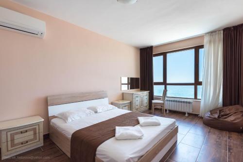 a bedroom with a large bed and a large window at Balchik Sea View Apartments in Princess Residence in Balchik