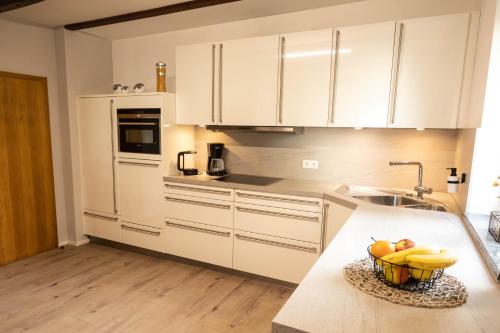 una cocina con armarios blancos y un bol de fruta en una barra en Rhön & Relax, en Wildflecken