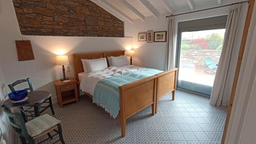 a bedroom with a bed and a table and a window at ATARAXIA at Saravari Beach-Almond House in Áyios Aléxandros