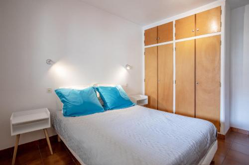 a bedroom with a bed with blue pillows and a cabinet at Location La Londe in La Londe-les-Maures