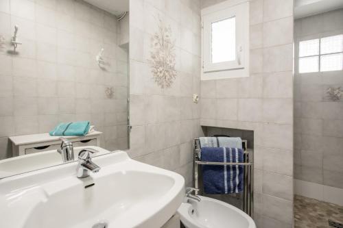 a white bathroom with a sink and a toilet at Location La Londe in La Londe-les-Maures