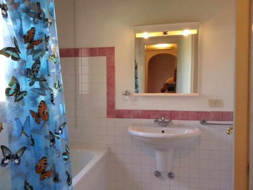 a bathroom with a sink and a shower curtain with butterflies at Villa Serena A in Stintino