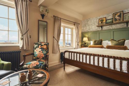 a bedroom with a bed and a chair and a table at The Rising Sun in Saint Mawes
