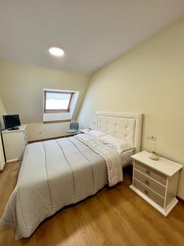 a bedroom with a large white bed and a desk at Centro de Miño - Pumariega in Miño