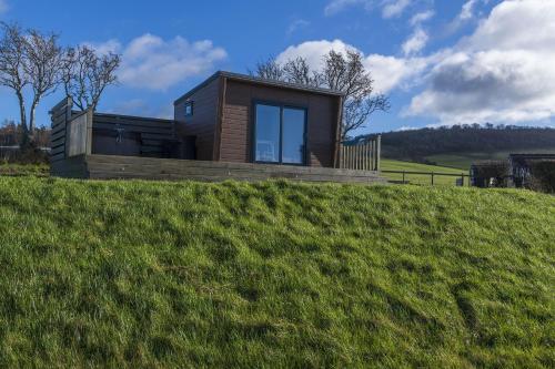 a house on top of a grassy hill at Waenfechan Glamping with Hot Tubs in Colwyn Bay