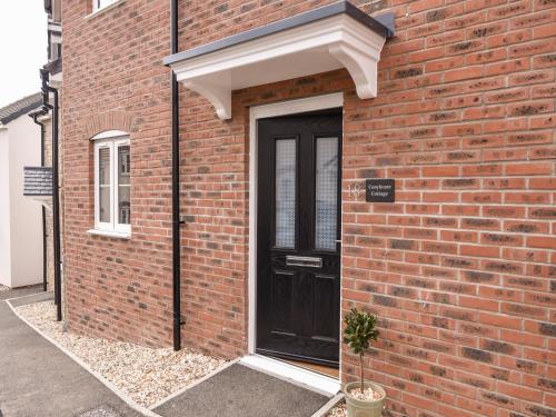 a black door on the side of a brick building at Conybeare Cottage in Lyme Regis