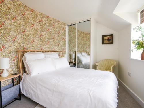 a bedroom with a bed and a wall with floral wallpaper at Conybeare Cottage in Lyme Regis