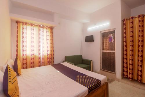 Un dormitorio con una cama y una silla verde. en SPOT ON Hotel Om Kanha, en Bilāspur