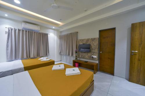 a hotel room with two beds and a tv at Hotel TrushaDham Near to Mahalaxmi Temple Kolhapur in Kolhapur