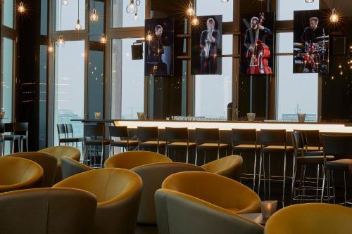 a restaurant with yellow chairs and a bar at HYPERION Hotel Hamburg in Hamburg