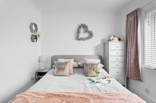 a white bedroom with a bed with pink pillows at Swan's Nest in Torcross