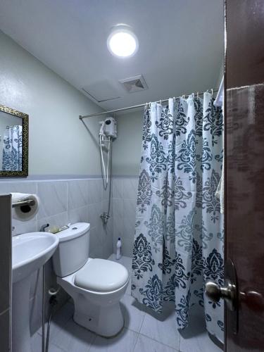 ein Bad mit einem WC und einem Duschvorhang in der Unterkunft Saekyung Condominium in Mactan
