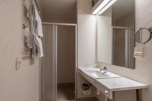 a bathroom with a sink and a shower with a mirror at Hotell Villa Sparta in Älvsbyn