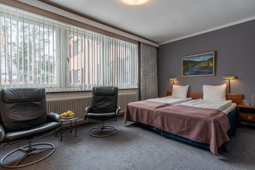 um quarto de hotel com uma cama e duas cadeiras em Hotell Villa Sparta em Älvsbyn