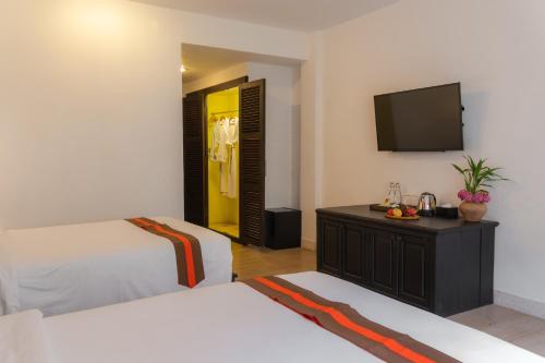 a bedroom with two beds and a flat screen tv at Pandora Suite D'Angkor in Siem Reap