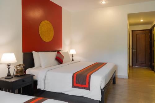 a hotel room with two beds and a red wall at Pandora Suite D'Angkor in Siem Reap