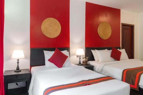 two beds in a hotel room with red and white at Pandora Suite D'Angkor in Siem Reap