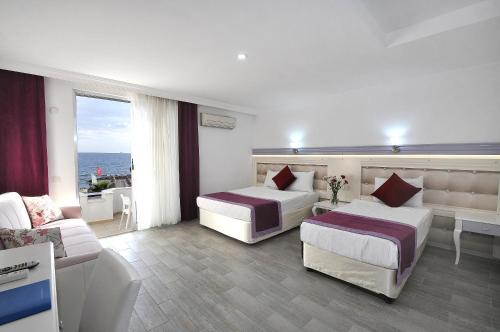 une chambre d'hôtel avec deux lits et un canapé dans l'établissement Ramira Beach Hotel - All Inclusive, à Avsallar
