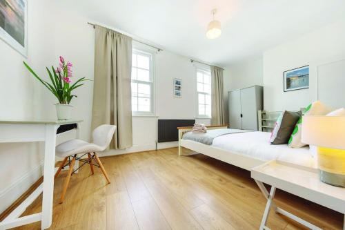 a white bedroom with a bed and a desk at Beautiful Flat in Westminster in London