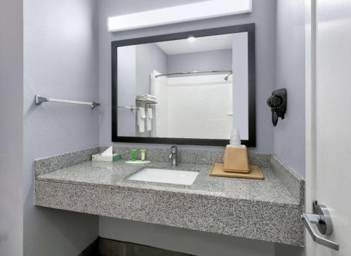 baño con lavabo y espejo grande en Days Inn by Wyndham Zachary LA, en Zachary