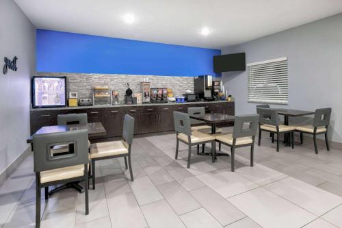 a dining room with tables and chairs and a bar at Days Inn by Wyndham Zachary LA in Zachary