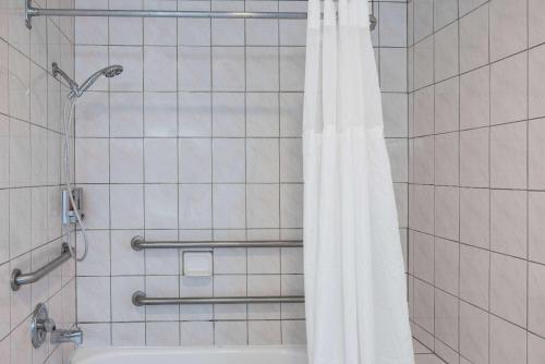 a shower with a white shower curtain in a bathroom at Oceanside Inn & Suites, a Days Inn by Wyndham in Fort Bragg