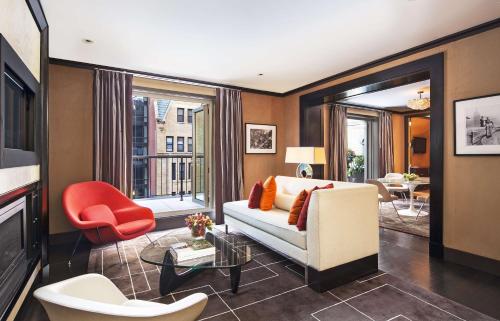 a living room with a white couch and a red chair at The Chatwal, New York by Hyatt in New York