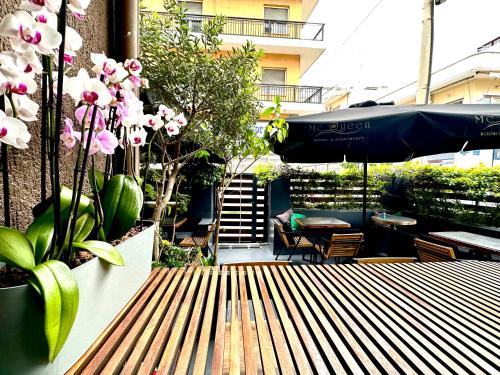 un banco de madera con plantas y una sombrilla en el patio en Mc Queen Rooms & Apartments, en Atenas