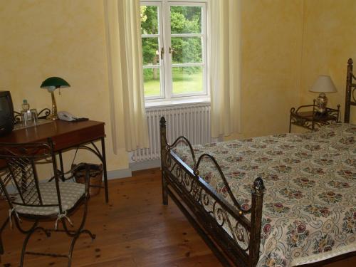 a bedroom with a bed and a desk and a window at Landhaus Schloss Kölzow in Kölzow