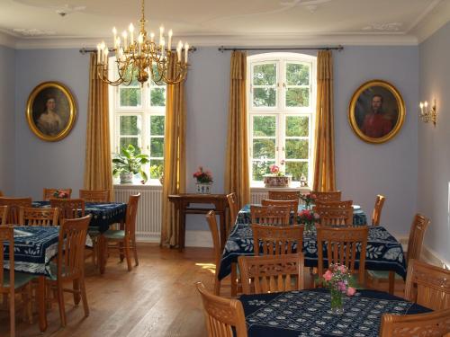 a dining room with tables and chairs and windows at Landhaus Schloss Kölzow in Kölzow